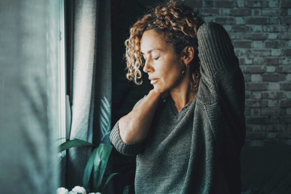 woman with radiating neck pain holder her neck and shoulder
