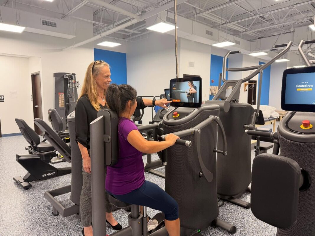 physical therapist showing patient how to use equipment